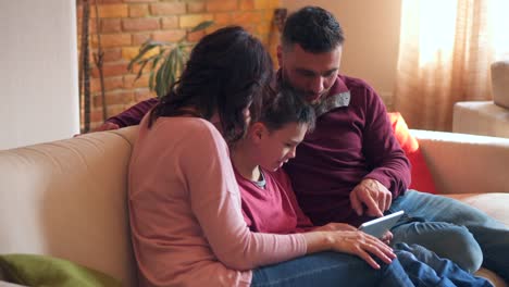 Family-of-three-using-digital-tablet-on-sofa