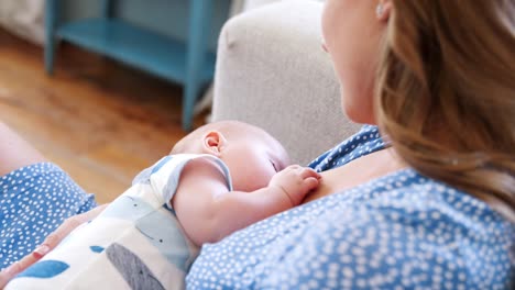 Nahaufnahme-Bild-von-Mutter-sitzt-auf-dem-Sofa-zu-Hause-stillen-Baby-Sohn-über-die-Schulter---Schuss-in-Zeitlupe-angesehen