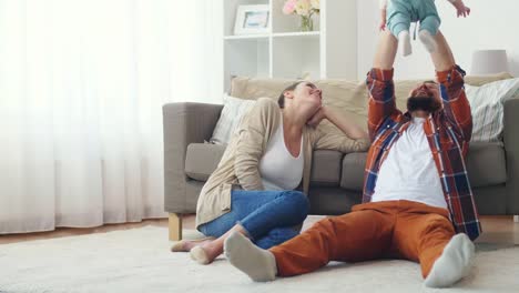 happy-mother-and-father-playing-with-baby-at-home