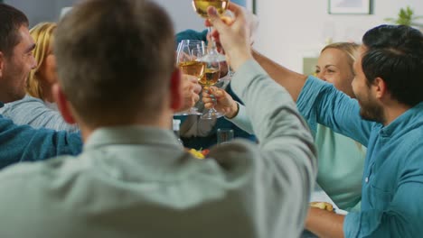 Große-Familie-und-Freunde-feiern-zu-Hause,-vielfältige-Gruppe-von-Menschen-versammelten-sich-am-Tisch-anstoßen-in-einem-Toast.-Leute-Essen,-trinken-und-Spaß-haben.-Tagsüber-Festlichkeit-im-Wohnzimmer.