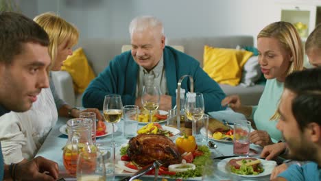 Große-Familie-und-Freunde-feiern-zu-Hause,-vielfältige-Gruppe-von-Menschen-versammelten-sich-am-Tisch-anstoßen-in-einem-Toast.-Leute-Essen,-trinken-und-Spaß-im-Wohnzimmer.