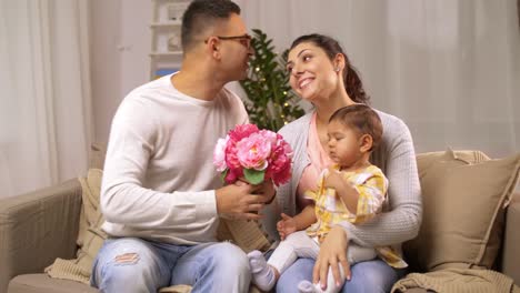 glückliche-Familie-mit-Babymädchen-und-Blumen-zu-Hause