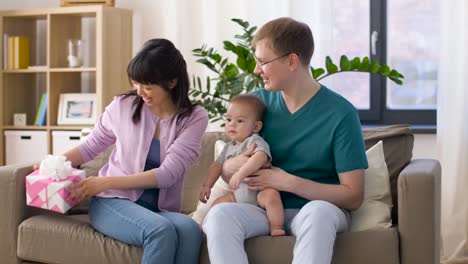 familia-feliz-con-el-regalo-y-bebé-niño-en-casa