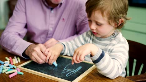 Padre-enseña-joven-para-escribir-con-tiza