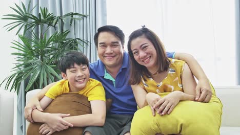 Slow-motion-of-asian-family-father-mother-and-son-on-couch,-Looking-at-camera--with-smile-face.