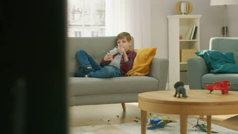 Adorable-Little-Boy-Laying-on-a-Couch-Playing-in-Video-Game-on-TV-Console-Using-Joystick-Controller.-Boy-Playing-in-Videogame-at-Home.