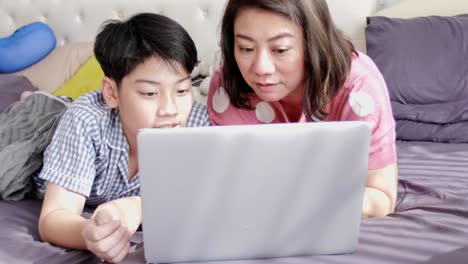 Glückliche-Familie-Mutter-und-Sohn-gerade-auf-Laptop-Computer-mit-Lächeln-Gesicht,-Slow-Motion-4K-asiatischen-Familie-Rest-auf-Bett-mit-Laptop-computer