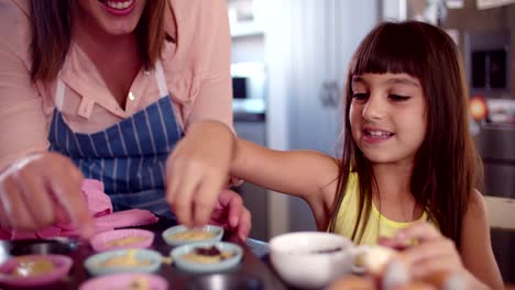 Mädchen-Dekoration-cupcakes-Sie-hilft,-ihre-Mutter-machen