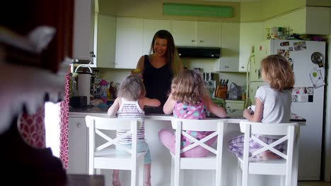 A-mother-talks-to-her-daughters-at-the-kitchen-counter-in-the-morning