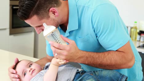 Sonriente-padre-dando-su-botella-de-bebé-niño