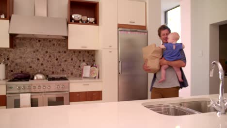 Modern-Dad-Unpacking-Groceries-with-Infant-Girl-In-Arms