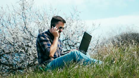 Transportwagen-Schuss.-Mann-mit-Bart-mit-Laptop-auf-Natur-in-der-Nähe-von-blühenden-Baum