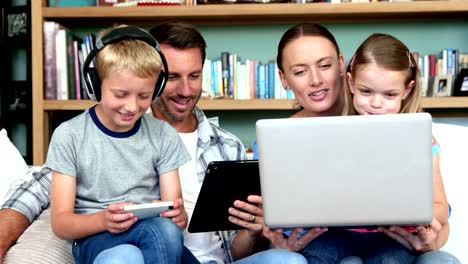 Lindo-familia-utilizando-tecnologías-sentado-en-un-sofá-cama