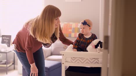 Madre-de-una-joven-de-pie-junto-un-su-bebé-sentado-sobre-un-cambio-de-mesa-en-un-jardín-de-infancia