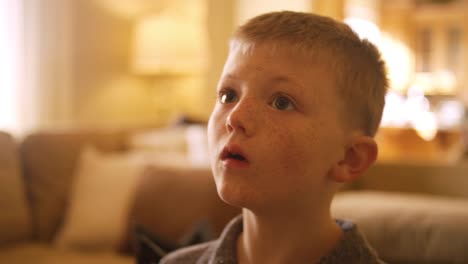 Little-boy-at-home-controlling-the-television-with-a-tablet,-close-up