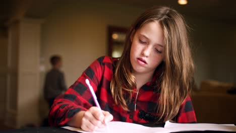 Young-teen-doing-homework-at-the-kitchen-table