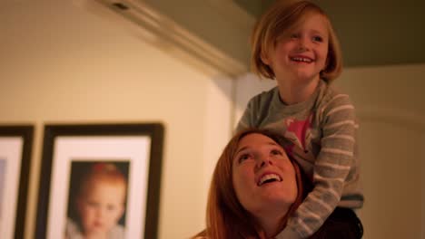 A-little-girl-sitting-on-her-mother's-shoulders-and-reaching-for-the-ceiling,-slow-motion