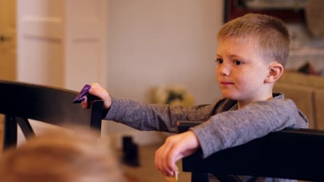 A-little-boy-standing-in-the-kitchen-eating-crackers-with-his-sister