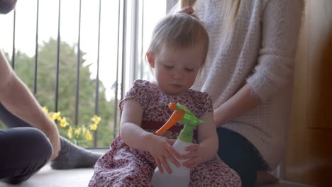 Young-Girl-With-Parents-Playing-With-Plant-Spray