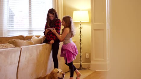 Two-friends-using-a-tablet-together-in-the-living-room,-view-through-a-doorway