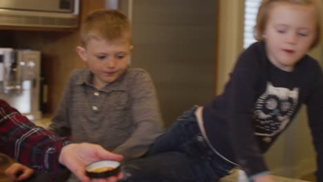 Niños-sentados-en-el-mostrador-de-la-cocina,-ayudando-a-su-pizza-de-hace-de-mamá