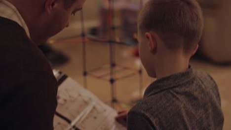 A-father-and-son-reading-instructions-and-building-a-plastic-toy-structure-together-at-home