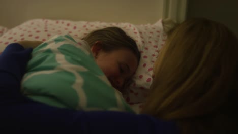 A-woman-tucking-her-daughter-into-bed