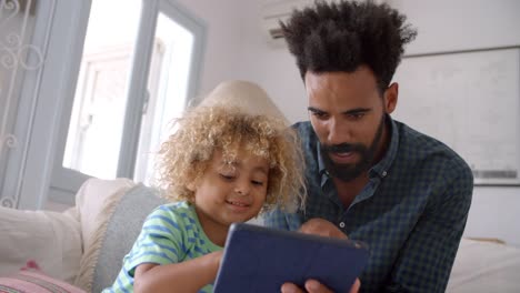 Vater-und-Sohn-sitzen-auf-Sofa-mit-digitales-Tablet