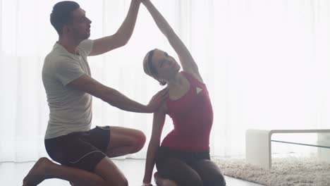 Mujer-y-hombre-haciendo-estiramiento-y-acondicionamiento-físico-en-sala-de-estar-en-casa.