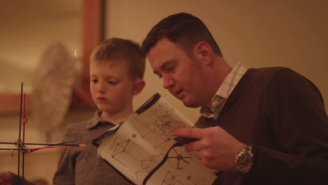 A-father-and-son-reading-instructions-and-building-a-plastic-toy-structure-together-at-home