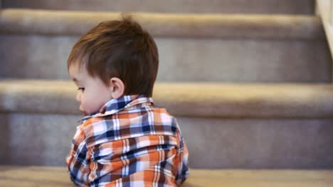 Kleiner-Junge,-der-unten-auf-der-Treppe-steht-und-einen-Sippy-Becher-hält