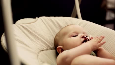 Adorable-little-baby-sway-on-swing-in-apartment.-Baby-dummy-in-mouth.-Family