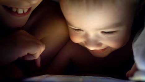 Two-young-brothers-playing-with-tablet-at-night.-4K