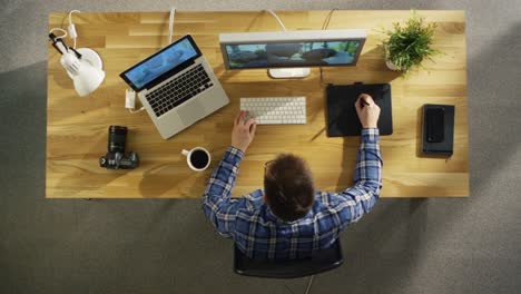 Top-View-of-Young-Talented-Photographer-Working-on-Digital-Drawing-Tablet-at-His-Desktop-Computer.-Processing-Wedding-Photography.-His-Workplace-is-Covered-with-Sunlight.