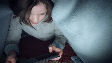 4k-Shot-of-Child-under-Blanket-Looking-on-Tablet