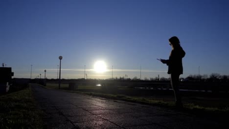 Mujer-utilizando-tablet-fuera-al-atardecer