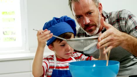 Father-helping-boy-to-filter-flour-using-a-strainer