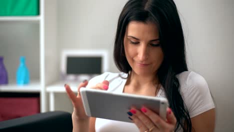 Junge-Frau-auf-ihrer-Couch-mit-ihrem-Tablet-zu-Hause-im-Wohnzimmer-entspannen