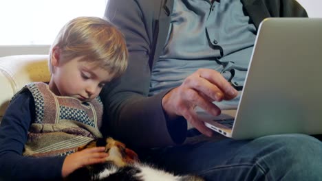 moderne-Familie-kleines-Mädchen-spielt-mit-Katze-während-Papa-arbeitet-mit-Notebook-auf-Couch-indoor-in-modernen-industriellen-Haus.-Kaukasische.-4k-handheld-nahaufnahme-Slow-Motion-video-gedreht