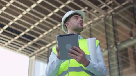 Männlicher-Ingenieur-mit-Tablet-Computer.-Glasbau-oder-Wolkenkratzer-unter-Bau-auf-dem-Hintergrund.