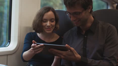 Man-and-Woman-are-Traveling-in-Train-and-using-Tablet-for-Entertainment