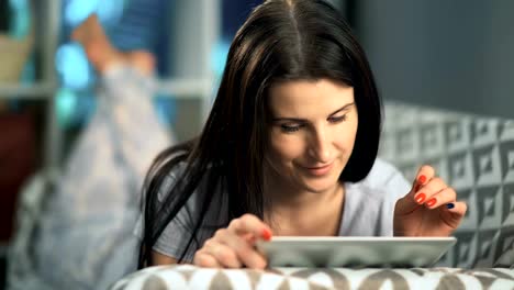 Beautiful-woman-using-tablet-lying-on-sofa-at-home