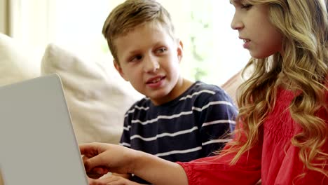 Siblings-using-laptop-in-living-room