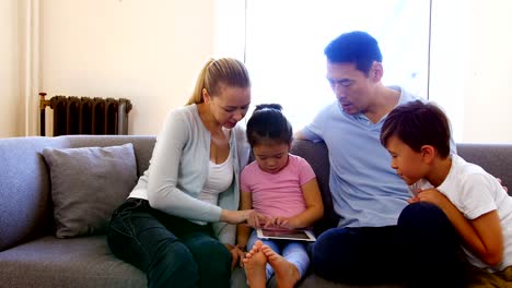 Glückliche-Familie-mit-digital-Tablette-im-Wohnzimmer