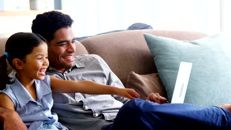 Father-and-daughter-using-laptop-in-living-room