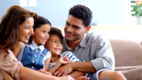 Feliz-familia-sentado-en-el-sofá-y-abrazando-en-sala-de-estar