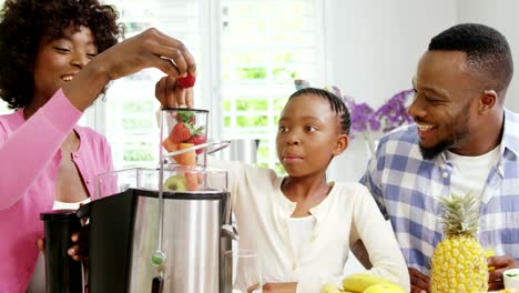 Mother-and-daughter-putting-strawberries-in-juicer