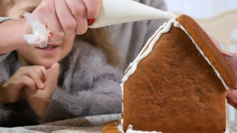 Die-Frau-legt-eine-weiße-Creme-auf-ein-Lebkuchenhaus