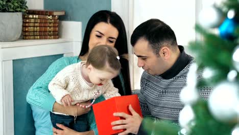 Familia-abrir-regalo-frente-a-árbol-de-Navidad