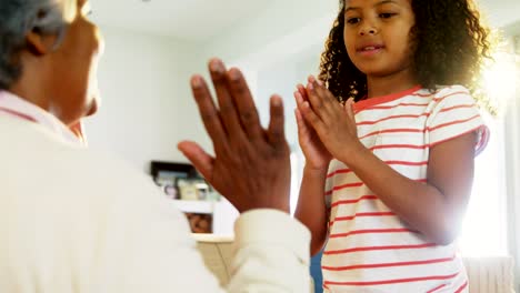 Granddaughter-and-grandmother-playing-clapping-games-in-living-room-4k